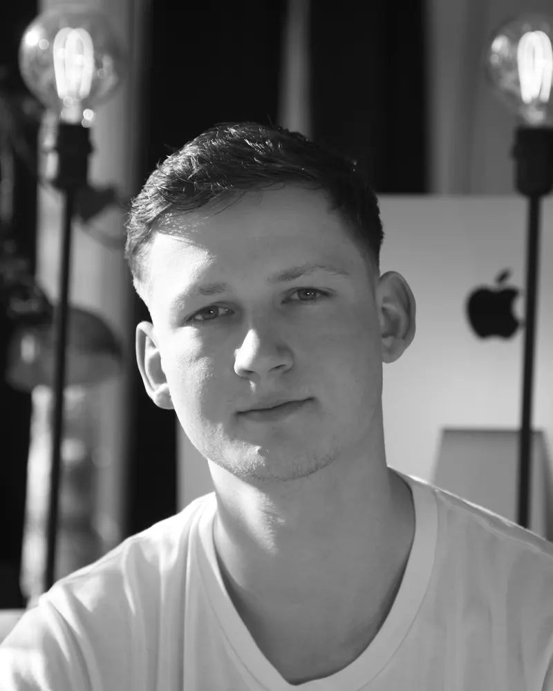 Porträt von Moritz Kunkel in Schwarz-Weiß, am Schreibtisch vor einem Bildschirm